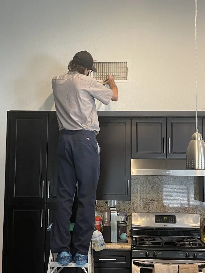 Technician inspecting an air vent during HVAC service in Milwaukee